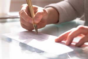 Picture of a person signing a check.